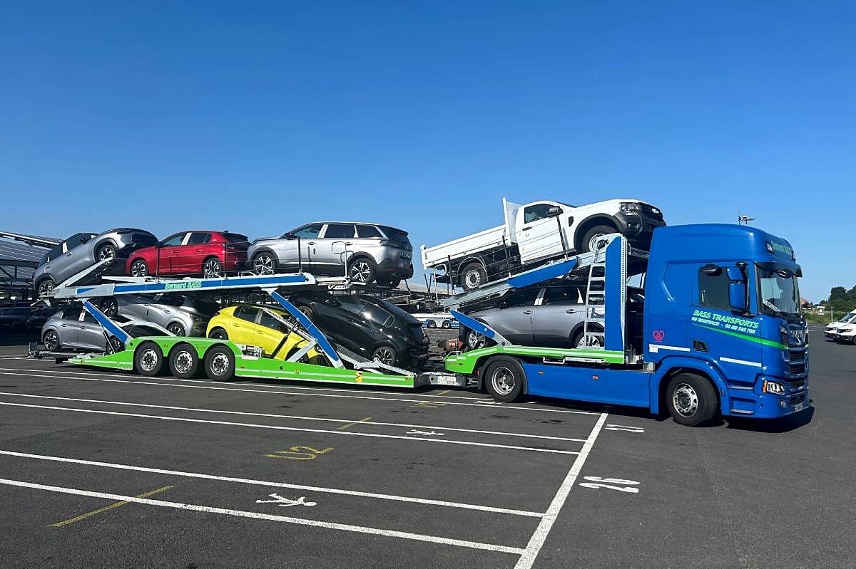 Trois porte-voitures Bernard Bass alignés sur le parking, chargés de véhicules